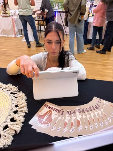 Eine Frau betrachtet ein Tablet, während sie an einem Tisch mit bunten Blättern sitzt.