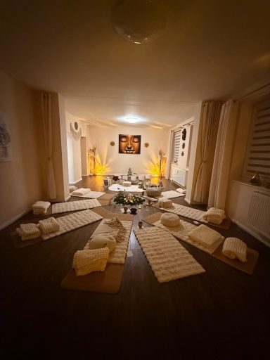 Ein heller Raum mit Matten und Kissen, umgeben von sanfter Beleuchtung und Dekoration.