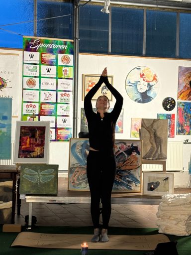 Eine Person steht in einer Yoga-Pose zwischen verschiedenen Kunstwerken.