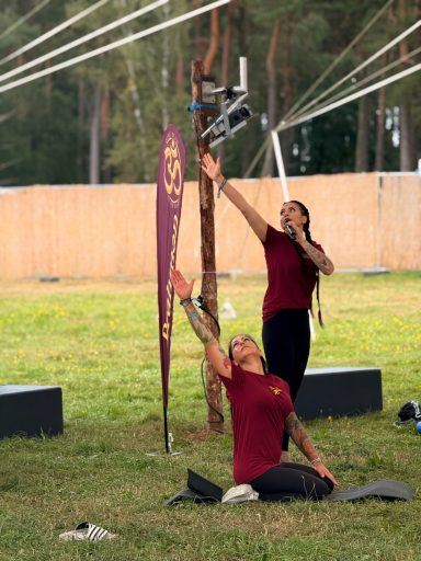 Zwei Personen in rot tragen eine akrobatische Pose im Freien.